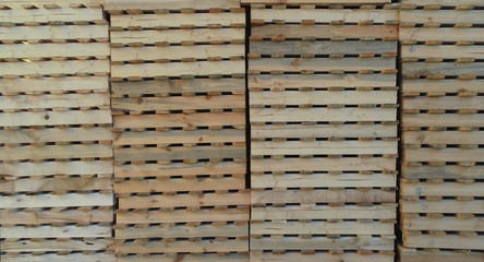 side view of a lot of yellow pallets standing on top of each other in a row in several columns