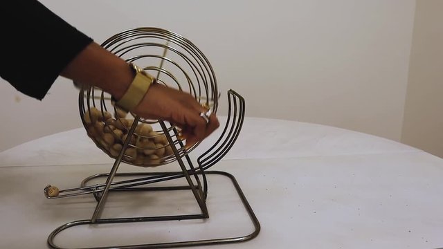 Woman Turns Bingo Machine On Table, White Background.