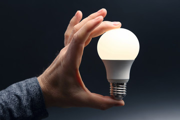 Included led new lamp in human hand on dark background