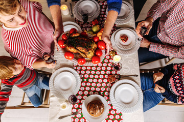 Grandmother serves Christmas Turkey on a festive table for a large happy family. Top view