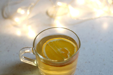 Cup of tea with slice of orange. Selective focus, fairy lights in the background.
