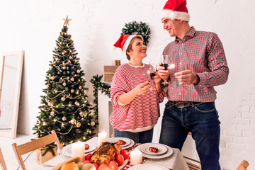 Happy family standing at Christmas table holding champagne with sparklers