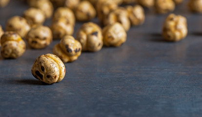 Obraz premium turkish leblebi, famous nut, close up yellow roasted chickpeas on black rustic vintage wooden background