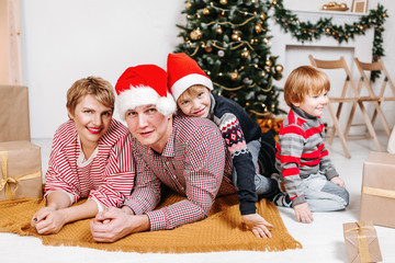 Happy family hugging each other lying on the floor on Christmas tree