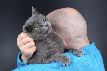 gray cat sitting on the shoulder of a man