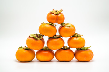 a pyramid of ripe orange persimmons isolated on white