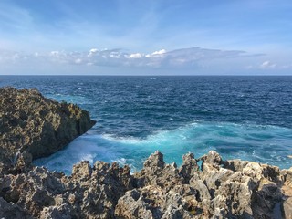 Ocean view with sharp rocks in the foreground and dark blue and green water in Nusa Dua Bali