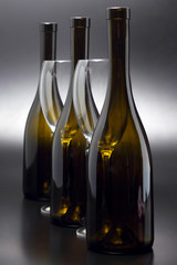Three wine bottles and two empty wine glasses close up