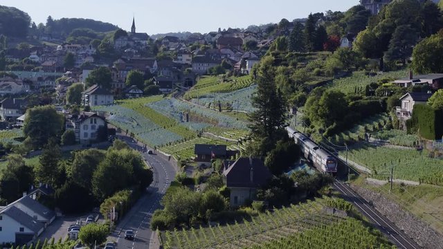 Aerial shot following Swiss train from behind, going through Lavaux vineyard and entering Chexbres village, Switzerland