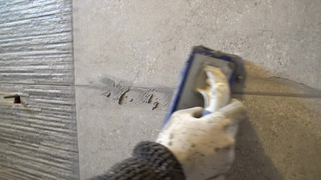 Worker putting fugue on the wall in bathroom. Grouting ceramic tiles, close up