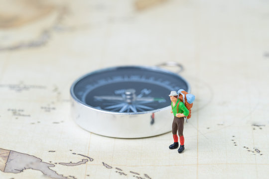 Travel, tourism or wanderlust life concept, plan for next destination, new adventure journey, miniature figure young man backpacker standing with compass on vintage world map.