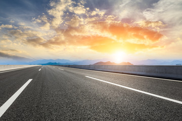 Asphalt road and mountains at beautiful sunset