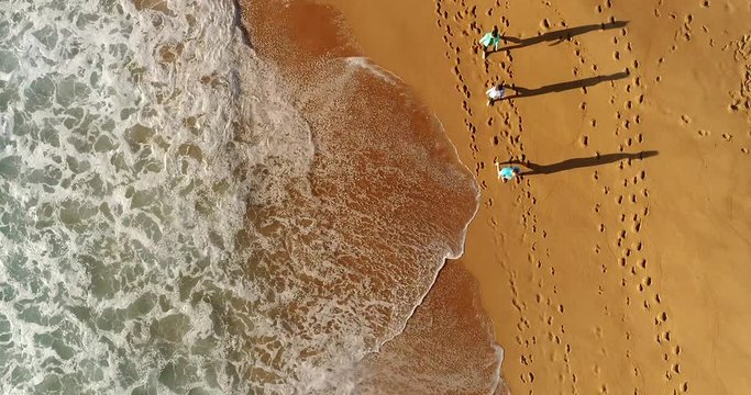 Waterfront of Pacific ocean around Sydney Northern beaches with active exercising people walking in waves on sands.
