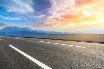 Asphalt road and mountains at beautiful sunset