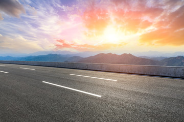 Asphalt road and mountains at beautiful sunset
