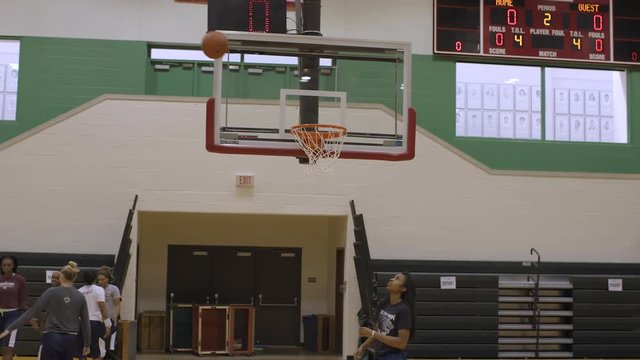 A female basketball player makes a three pointer at practice in slow motion