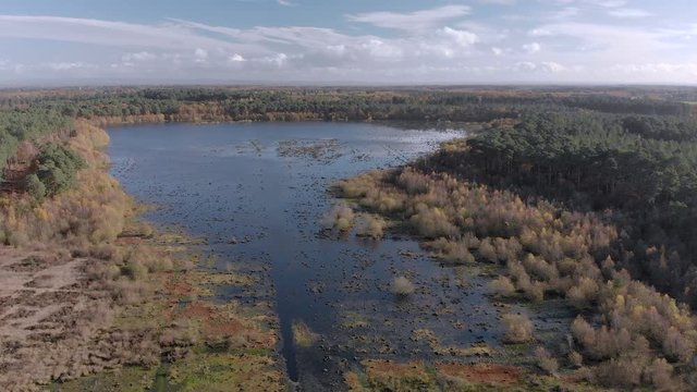 Ariel flight over the south part of Blakemere Moss lake at Delamere Forest, Cheshire, England during autumn