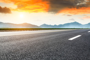 Asphalt road and mountains at beautiful sunset