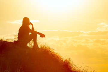 Silhouette of a sad young lonely girl with a smartphone at sunset