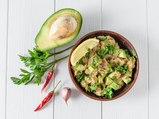 Salad of amaranth, avocado, pepper, lemon and parsley seeds with olive oil on a white wooden table. The view from the top.