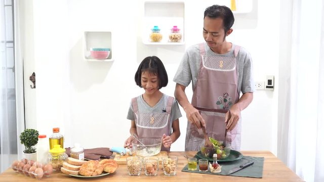 Father and daughter cooks in the kitchen at home, happy family asian concept