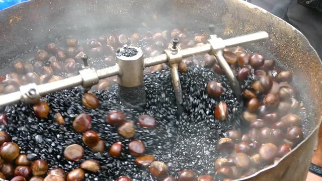 Slow Motion medium close up of a Traditional Malaysian Coffee Roaster at a market in Kuala Lumpur. It is greasy, smoky and a blend of Hazelnut and dark coffee beans.