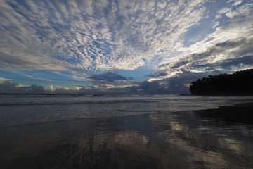 Sunset over the beach of Playa El Coco, Nicaragua, with a colorful cloudscape reflected in the coastal water.