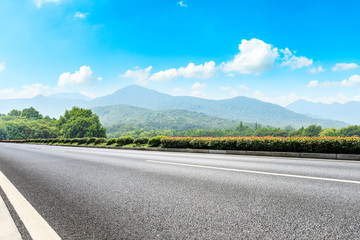 Asphalt road and mountains with white clouds