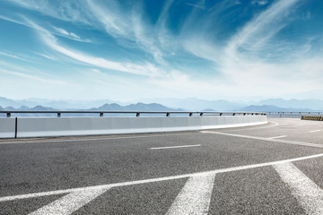 Asphalt road and mountains with white clouds