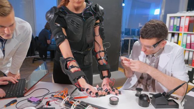 Woman manipulating robotic arm with sensors on her hand