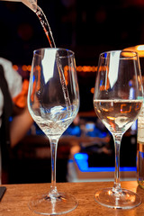 Pouring white wine into glasses in the vineyard, toned