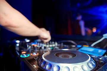 Naklejka premium Dj mixes the track in the nightclub at party. Headphones in foreground and DJ hands in motion