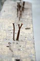 A close up image of rusty nails on a wooden bar in a modern house construction site.