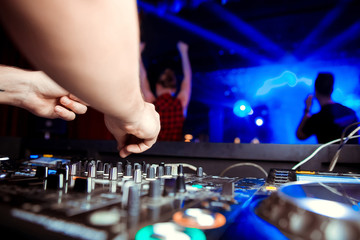 DJ turntable console mixer controlling with two hand in concert nightclub stage.