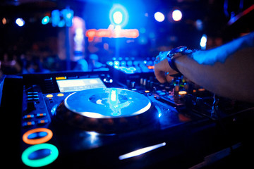 Fototapeta na wymiar DJ turntable console mixer controlling with two hand in concert nightclub stage.