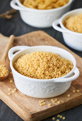 Uncooked anellini pasta in a bowl on wooden background