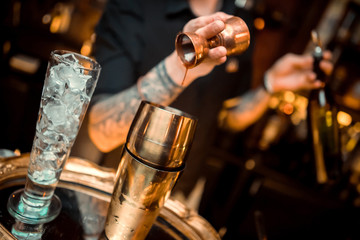 Fototapeta na wymiar whiskey poured into a glass with ice using a steel dispenser