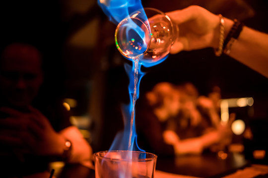 Glass with burning alcohol. Image of two glasses of burning emerald absinthe. Glass of tequila and flames
