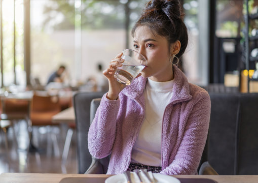woman drinking a glass of water in restaurant