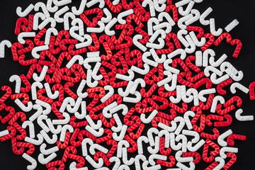 Red and white candy cane sprinkles scattered on a black background