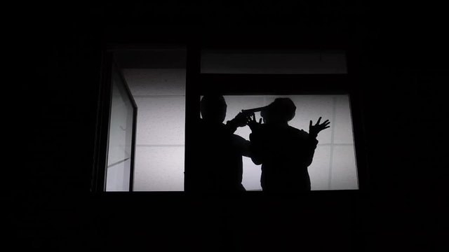 Silhouette of robber putting gun to female victim temple, penetration to home