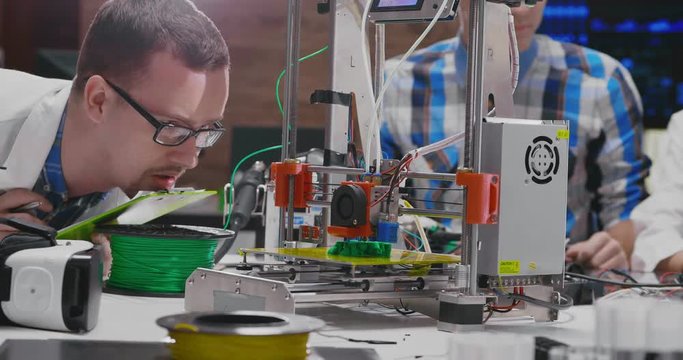 Male engineer watching with interest how 3d printer