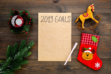 Goals list for New Year 2019 mockup near new year background like spruce branch, candle, socks on dark wooden background top view