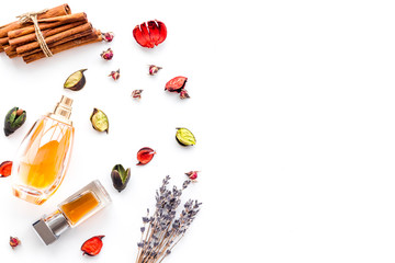 Perfume with bright fruity, floral, spicy fragrance. Ingredients for perfume. Bottle of perfume near dry flowers, cinnamon and candles on white background top view pattern space for text