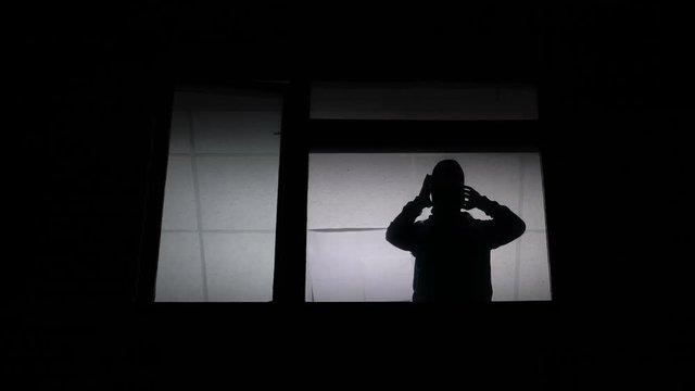 Silhouette at window putting on balaclava and leaving, getting ready for crime