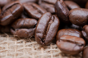 Macro shot of whole bean organic smooth medium dark roast coffee from Sumatra on burlap background.