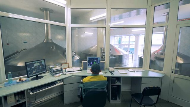 Male technician is controlling alcohol-producing process from his office