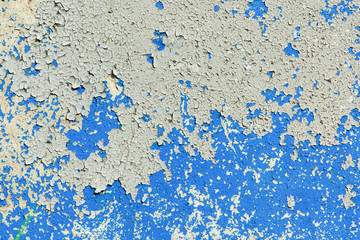 light coloured blue peeling paint on the old rough concrete surface