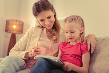 Pleasant cute girl doing her homework with her mother