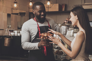 Male barista helps a girl to choose a dessert